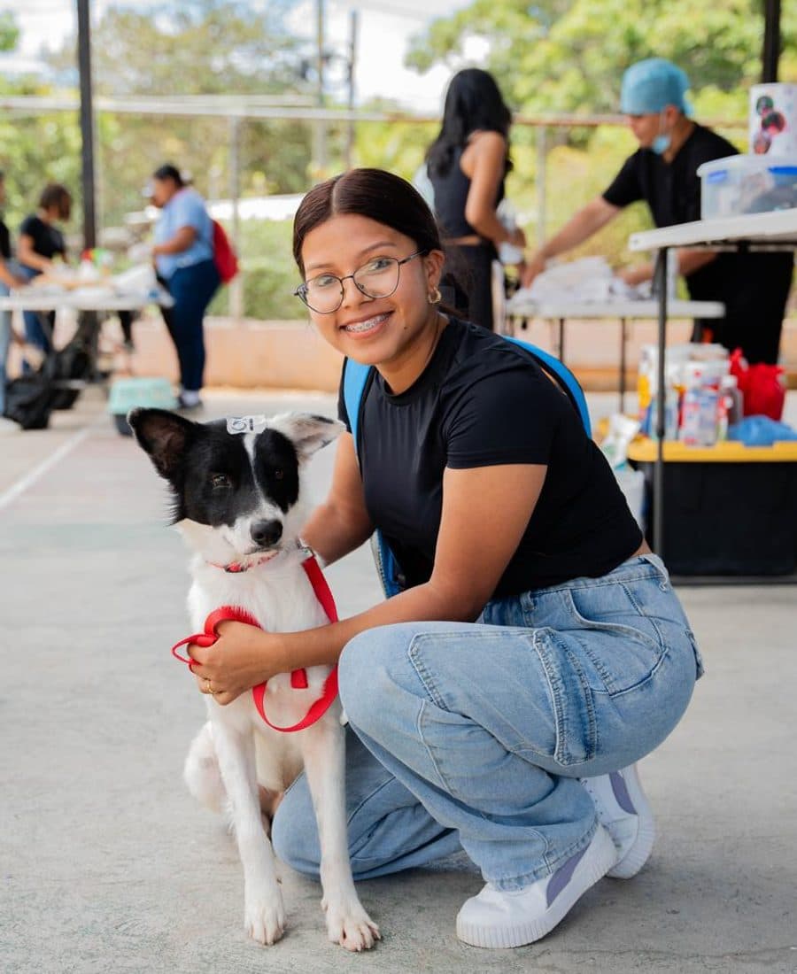 Voluntaria de Colitas Coclé sonriendo junto a un perrito en una jornada